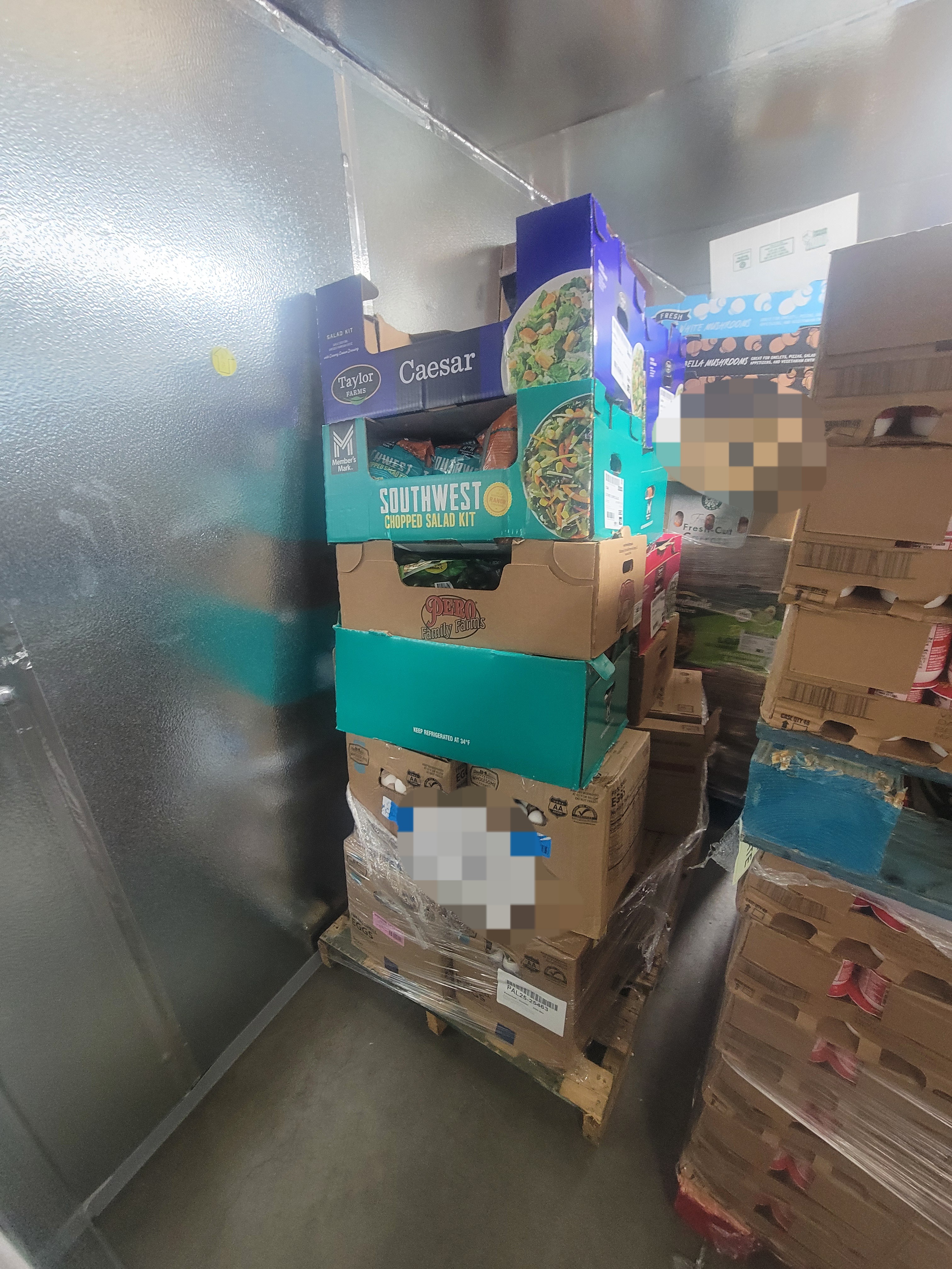 Pallets of boxes of produce in plastic wrap in a fridge box unit .